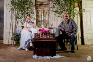 Mājas kafejnīcu dienu saimnieki sēž pie galda ar desām.